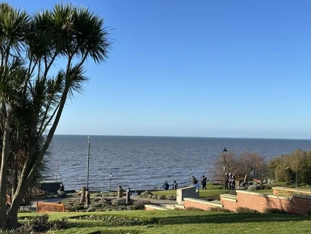 Clifftop gardens with palms, benches and low brick walls overlooking the sea