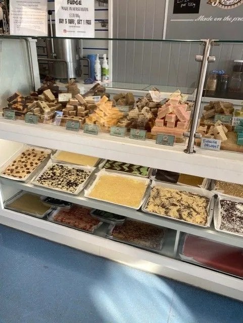 A shop counter filled with trays and slabs of fudge in many flavours and colours